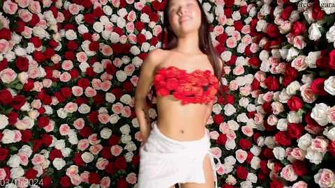 Media: Video of a smiling, petite Asian woman with long black hair, wearing a red lace bandeau top and white high-waisted shorts, set against a backdrop of red and white roses.