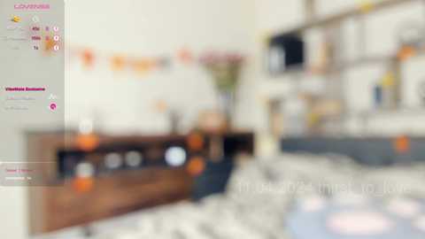 Media: This is a video of a modern, cluttered bedroom with a bed covered in a patterned white and grey comforter. The room is filled with various objects, including a wooden dresser and a TV on the wall. The background is out of focus, creating a soft, blurred effect.