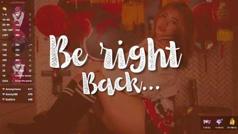 Media: Video of a woman in a red plaid skirt, white top, and thigh-high black socks, lying on a bed, with text overlay saying \"Be right back...\" in a playful font.