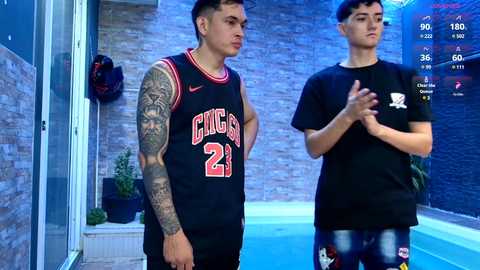 Media: Video of two men in black basketball jerseys, one with tattoos, standing by an indoor pool with blue tiles and a stone wall background.