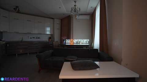 Media: Video of a modern, minimalist living room with dark furniture, a white coffee table, and a large TV screen displaying \"\u0413\u043e\u0432\u043e\u0440\u0438\u0442 \u041c\u043e\u0441\u043a\u0432\u0430.\