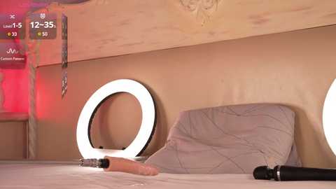 Media: Video of a modern bedroom with beige walls, round mirror with backlight, gray pillow, and a dildo on a bed. The room is lit by warm red light, creating a cozy atmosphere.