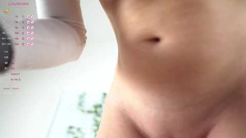 Media: A close-up video of a nude, fair-skinned person with a flat stomach and no visible body hair. The background is blurred with a hint of green plants. A digital calendar with the date \"05/13\" is visible on the left.