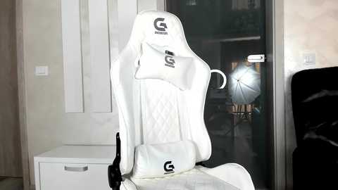 Media: A video of a white gaming chair with a G-TRONIC logo, positioned in a minimalist room with a white door and a black TV on the right.