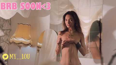 Media: Video of a nude Asian woman with medium breasts, long hair, and brown eyes, standing in front of a mirror, surrounded by white drapes and a yellow lamp, with text \"MY LOU\" and \"BKB SOON\" in the corners.