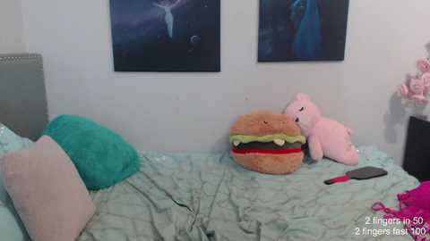 Media: Video of a messy bedroom with a large plush burger on a bed, two stuffed animals, and a pink phone charger.