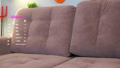 Media: Video of a beige sectional sofa with a digital interface overlay, displaying options like \"Add Friends\" and \"Change the Design.\" Background shows a vibrant orange wall and green potted plant.