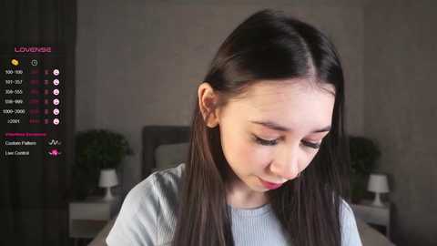 Media: Video of an East Asian woman with long black hair, wearing a light grey sweater, sitting indoors, with a virtual chat interface overlay.