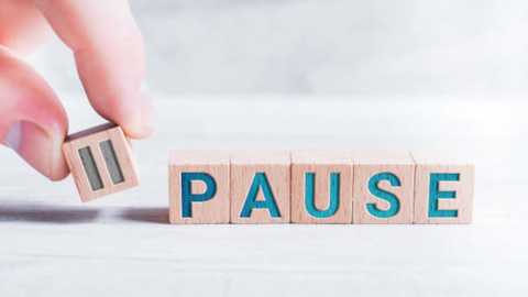 Media: A video of a hand holding a wooden block puzzle piece with the letter \"P\" on a light-colored, textured surface. The word \"PAUSE\" is partially visible in the puzzle, emphasizing the concept of taking a break.