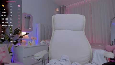 Media: Video of a modern, minimalist bedroom with a white chair and bed, soft lighting, and pastel-colored decor, including a flower vase.