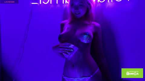 Media: Video of a nude, slim, blonde woman with medium breasts and pasties, standing against a purple-lit wall. She wears white panties.