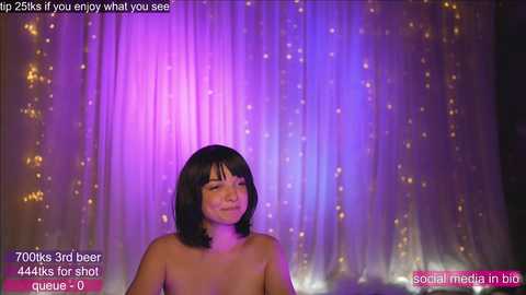 Media: Video of a nude Asian woman with straight black hair, wearing a serene expression, standing against a purple and blue draped background. Text overlays indicate she's a 70-year-old model, drinking 700ml of beer.