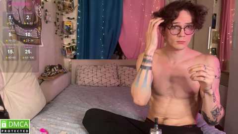 Media: Video of a shirtless, slender, androgynous person with short, curly hair, glasses, and tattoos, adjusting their hair in a pink and blue bedroom with a TV displaying \"DMCA Protected\" watermark.