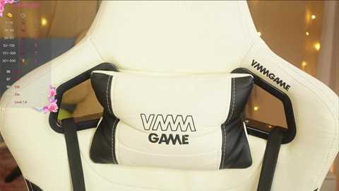 Media: Video of a white gaming chair with black accents, featuring the VMM Gaming logo, in a cozy, dimly lit room with fairy lights.