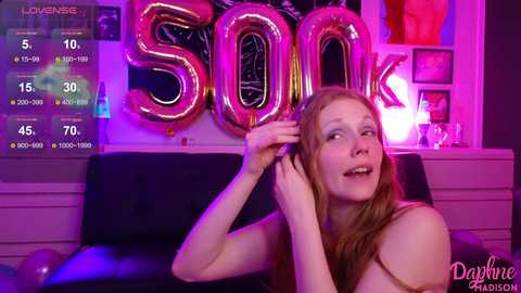 Media: Video of a fair-skinned, red-haired woman in a black strapless top, smiling while adjusting her hair, surrounded by neon \"SOUL\" letters and a digital display.