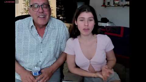 Media: A video shows an elderly man in glasses and a patterned shirt, and a young woman in a low-cut top, seated together, indoors.