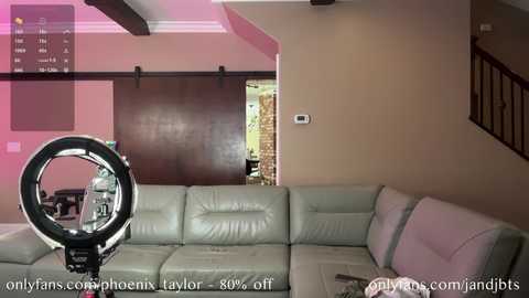 Media: A video of a modern living room featuring a white leather sectional sofa, a large circular light, and a sliding barn door in the background. The room is lit with warm pink lighting.