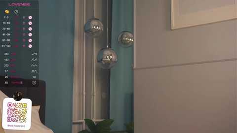 Media: Video of a modern living room with teal walls, featuring three spherical pendant lights and a digital clock displaying \"LOUNGE\" on the left.