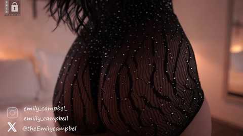 Media: Video of a woman's curvaceous backside clad in a sheer, sparkly black bodysuit, revealing her ample buttocks. Warm, ambient lighting highlights the texture of the fabric. Social media handles are visible.