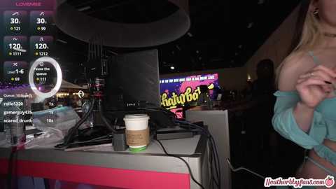 Media: Video of a dimly lit bar, with a virtual reality headset, a laptop, and a drink on a table. A partially visible woman with a large breast is in the background.