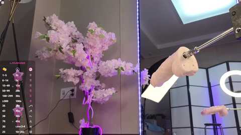 Media: A video showing a man's hand being placed inside a white plastic glove, with a cherry blossom tree and a ring light in the background.