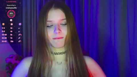 Media: Video of a young woman with long brown hair, wearing a black choker and red lipstick, in a dimly lit room with purple and blue lighting.