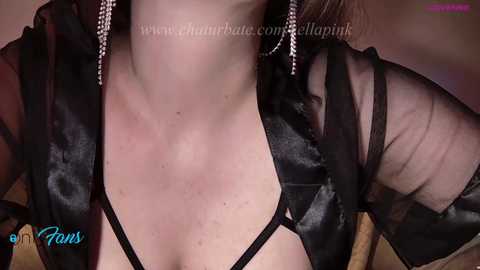 Media: Video of a woman in a black sheer robe, revealing her cleavage, with a close-up focus on her neck and upper chest.