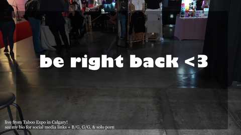 Media: Video of a dimly lit indoor event space with a polished concrete floor, featuring a white text overlay: \"be right back <3.\" People are blurred in the background.