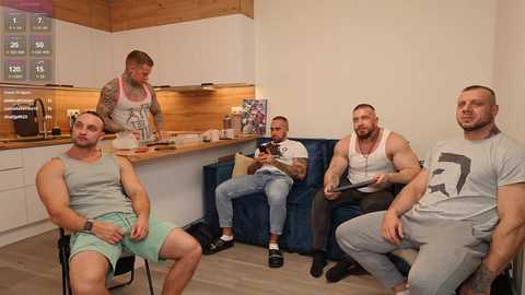 Media: Video of four muscular men in casual clothes sitting in a modern, wooden kitchen, one preparing food.