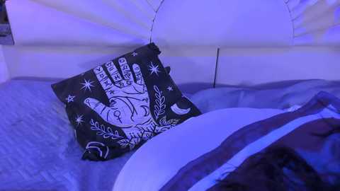 Media: A video of a person sleeping with a black pillowcase featuring a white astrological hand symbol and crescent moon, in a dimly lit room with blue light.