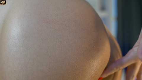 Media: A close-up video of a person's bare, light-skinned buttocks, with a hand gently caressing the skin, creating a warm, intimate atmosphere. The background is blurred, focusing on the smooth texture and softness of the skin.