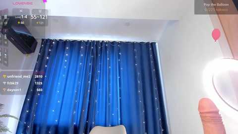 Media: A video of a bedroom with a large blue curtain adorned with white stars, a small TV mounted on the wall, and a bright lamp emitting a soft glow.