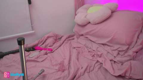 Media: Video of a messy bedroom with a pink bed, a stuffed animal, a vibrator, and a purple light strip, creating a whimsical, erotic ambiance.