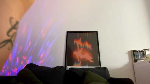 Media: A video of a modern living room with a large abstract painting of a flaming horse on a white wall. The sofa features dark green and black cushions. A colorful neon sign in the background adds a vibrant, trippy atmosphere.