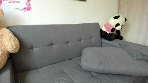 Media: Video of a modern gray sectional sofa with plush cushions and a large white teddy bear in the background.