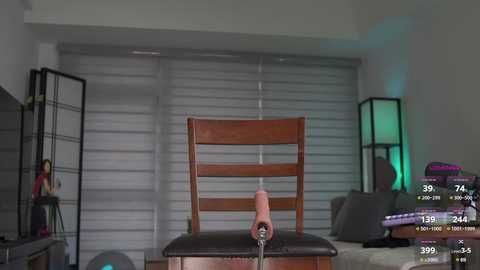 Media: Video of a woman in a red dress standing in a modern, minimalist room with a wooden chair and blinds.