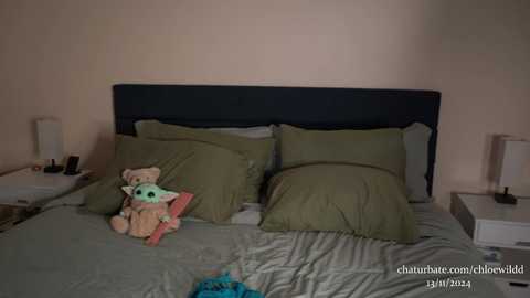 Media: A video of a messy bed with a Star Wars-themed plush toy, green pillows, beige walls, and a dark headboard.