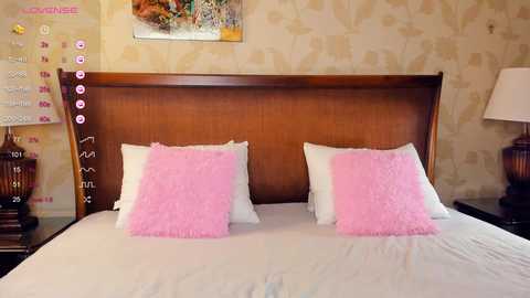 Video of a cozy bedroom with a wooden headboard, two white pillows, and two pink fluffy pillows on a neatly made bed.