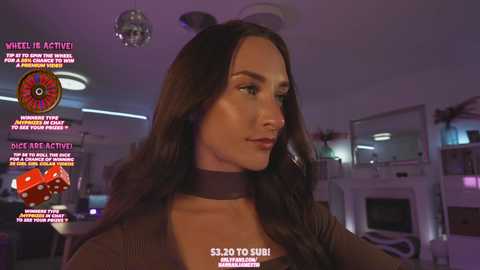 Media: Video of a woman with long brown hair and light skin, wearing a brown top, in a dimly lit, modern room. Background includes a disco ball, gaming equipment, and a roulette wheel. Text overlays with game instructions.