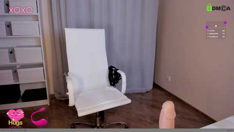 Media: Video of a modern room with a white ergonomic office chair, a black purse on the floor, and a pair of pink high heels on the wooden floor.