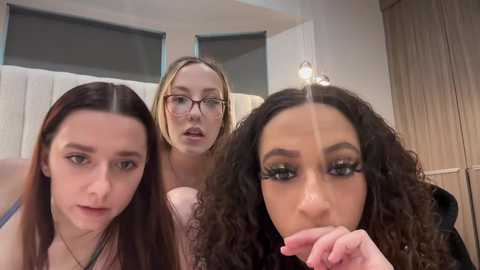 Media: Video of three women in a bathroom, with one woman licking her fingers, one with glasses, and another with curly hair.