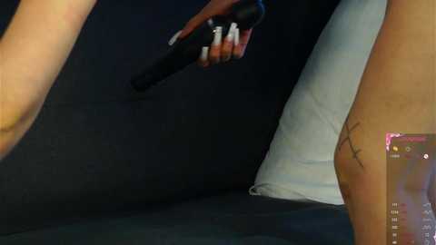 Media: A video shows a woman with fair skin holding a black handgun, her arm tattooed with a small star. She is partially dressed in a white garment, against a dark backdrop.