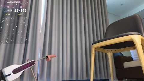 Media: Video of a modern room with a gray curtain, a wooden chair, and an exercise bike displaying \"5:59:99\" on a digital display.