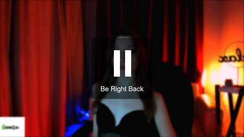 Media: Video of a dimly lit room with red curtains, a woman in a black dress, and a \"Be Right Back\" overlay.