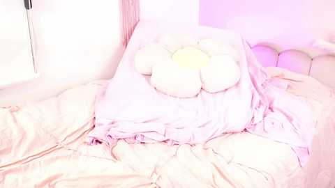 Media: Video of a pink and white bed with a tufted headboard, covered in a ruffled, light pink duvet. A plush, white bunny with a yellow bow sits atop the bedding.