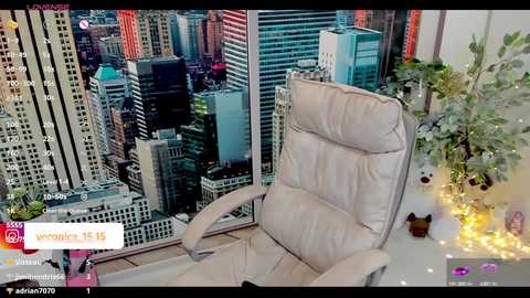 Media: Video of a plush beige armchair in a modern office with large glass windows overlooking a bustling cityscape at night.