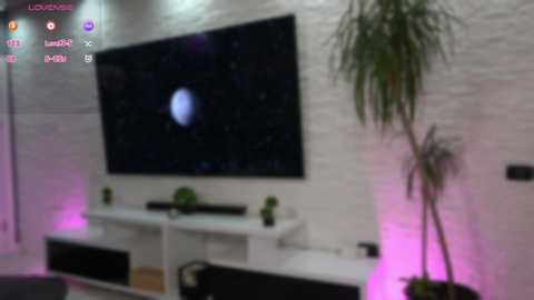 Media: Video of a modern living room with a large black TV screen displaying Jupiter, white brick wall, and a potted plant.