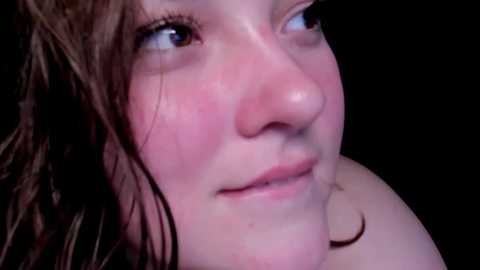 Media: Video of a young woman with fair skin, wet hair, and pink cheeks, gazing upward with a neutral expression.