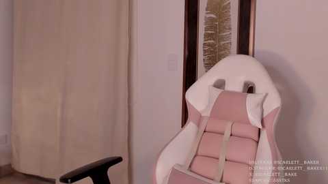 Media: Video of a modern, white leather recliner chair with a pink cushion, set against beige curtains and a framed forest scene in a minimalist room.