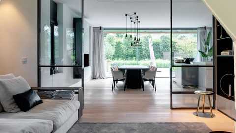 Media: Video of a modern, minimalist dining room with a large glass wall, light wood floors, white curtains, and a sleek black dining table with white chairs.